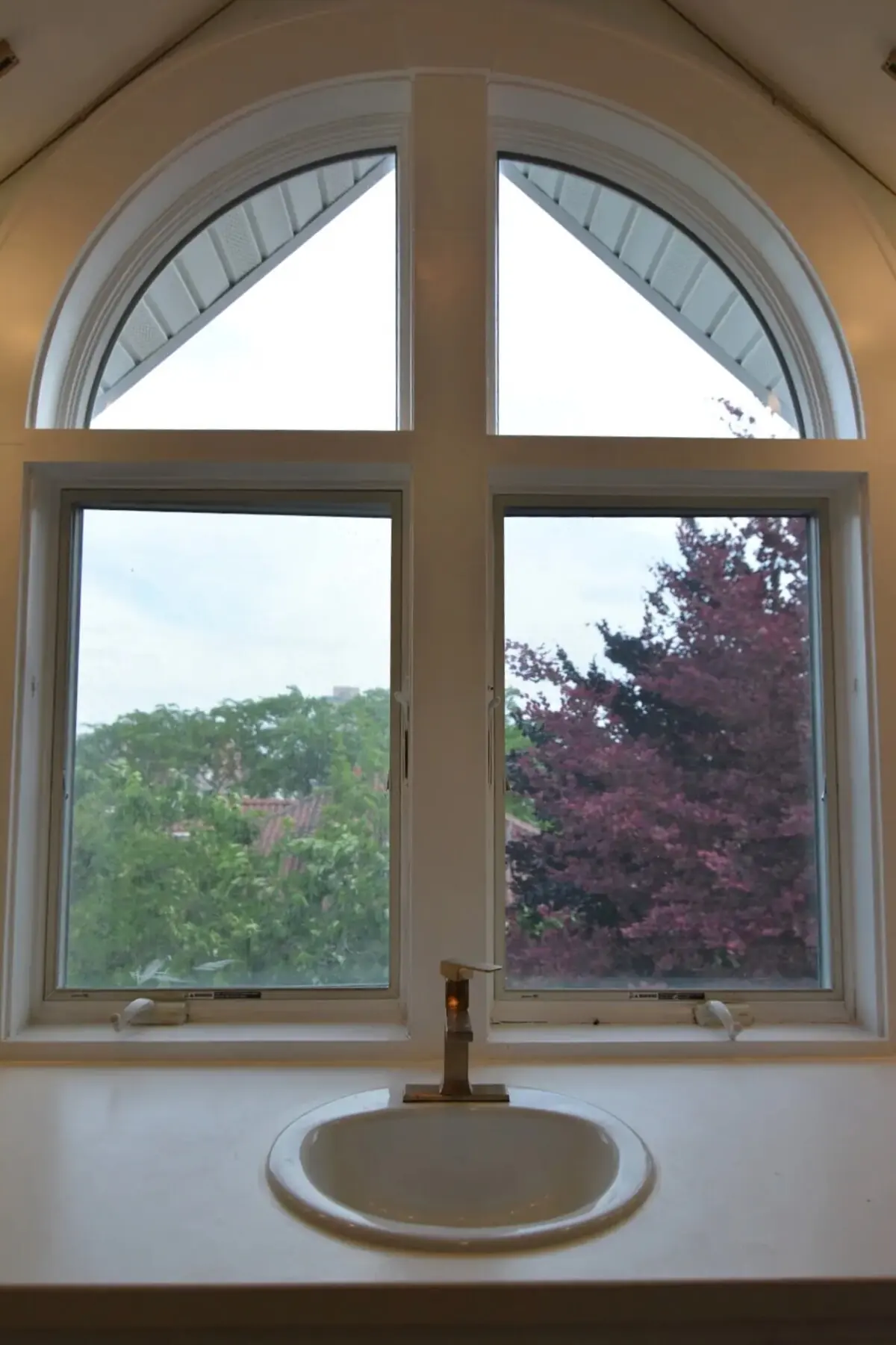 The suite bath sink and brass faucet beneath the south arched window, looking out on the beech in the back yard