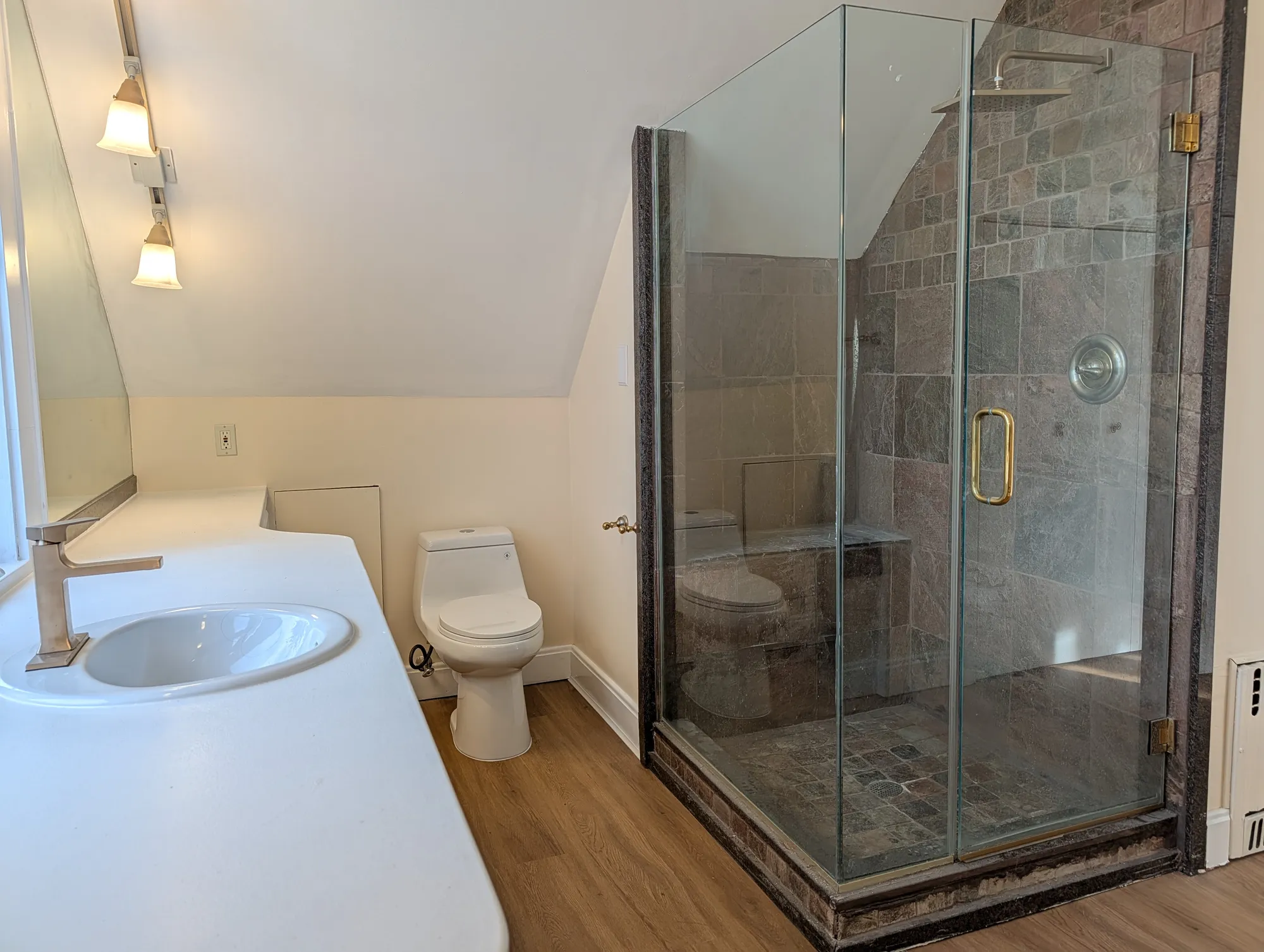 Suite bath with a frameless glass shower, vanity with brass fixtures, and its own window