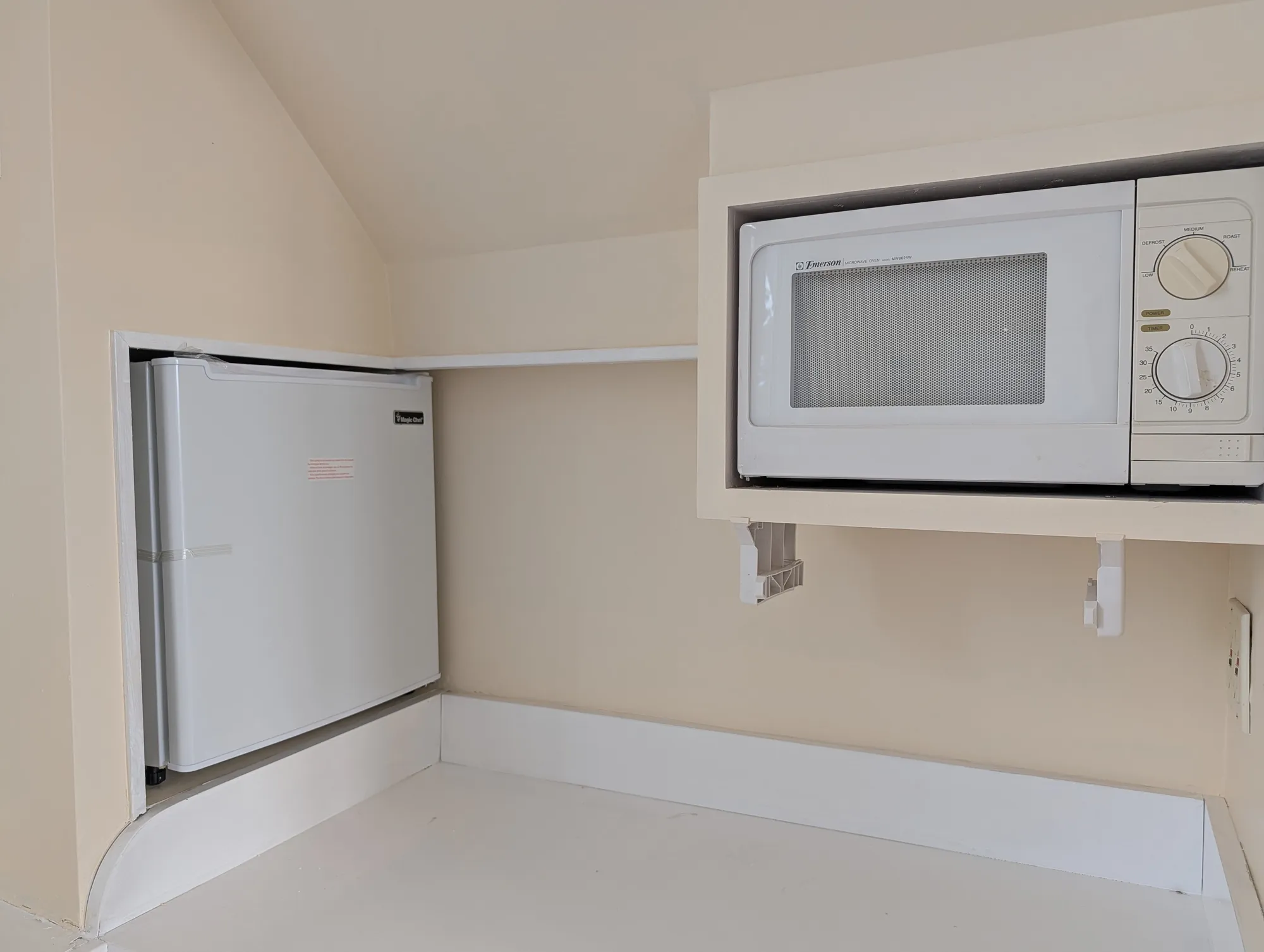 A kitchenette built under one of the arched windows in the suite, with cabinetry and a sink