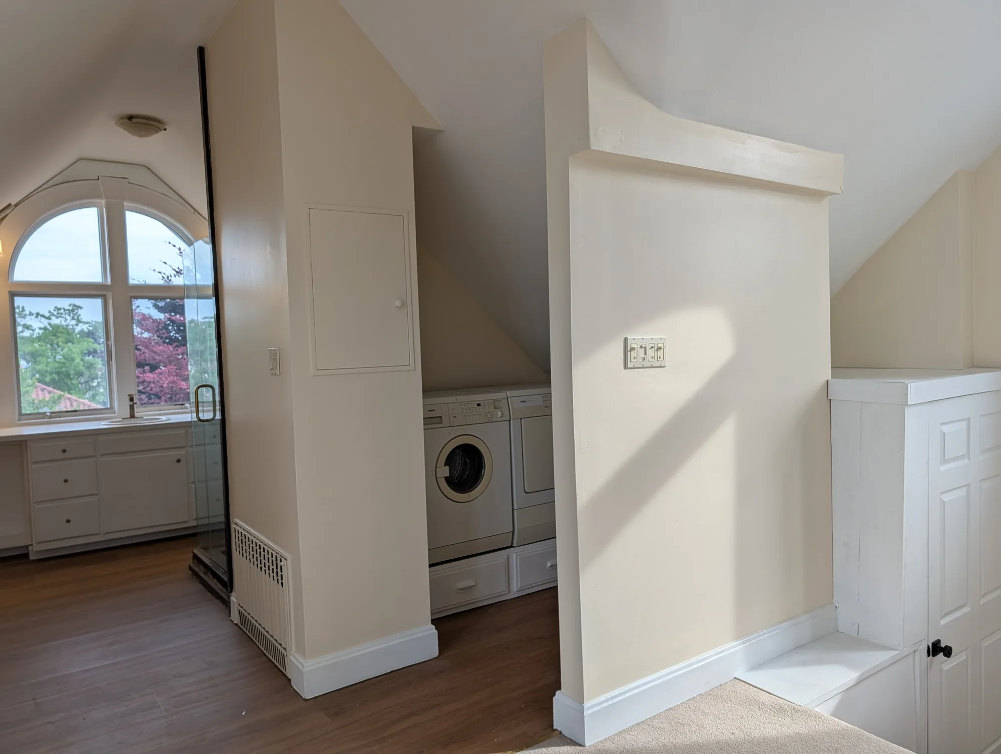 A washer and dryer tucked under the eave on the suite floor, on a built-in drawer base