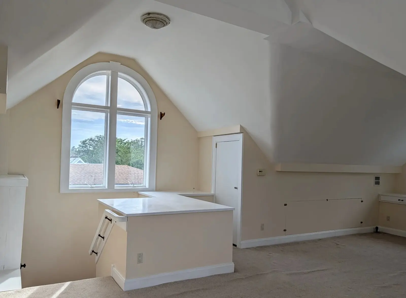The west end of the suite under the vaulted ceiling, arched window over the rooftops, the internal stairwell coming up in the foreground